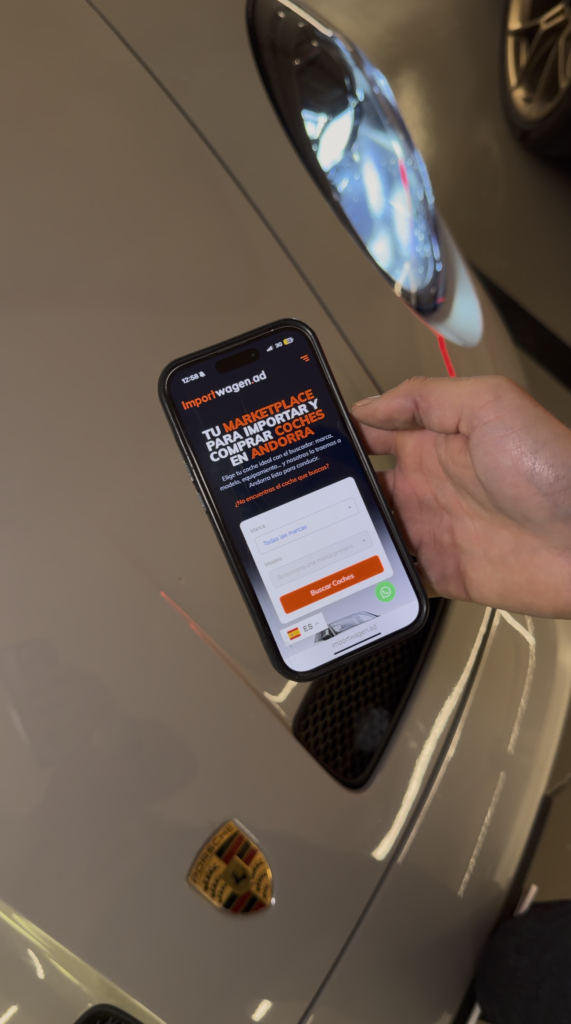 Persona usando el buscador de Importwagen en el móvil para importar y comprar un coche en Andorra frente a un Porsche.