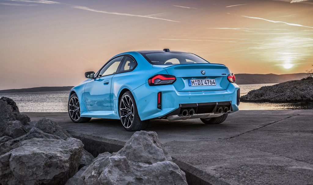 Vista trasera de tres cuartos del nuevo BMW M2 xDrive azul con cuatro tubos de escape al atardecer, ideal para importar a Andorra con Importwagen.